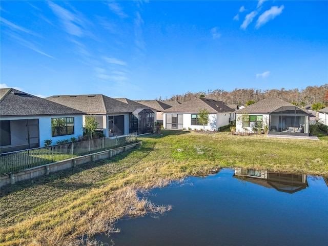 back of property with a water view, a lanai, and a yard