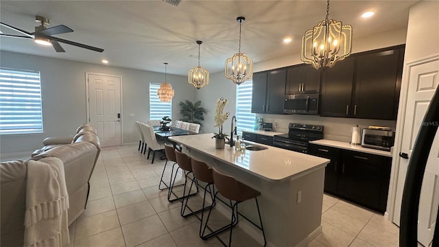 kitchen featuring decorative light fixtures, sink, a kitchen island with sink, light tile patterned floors, and electric range