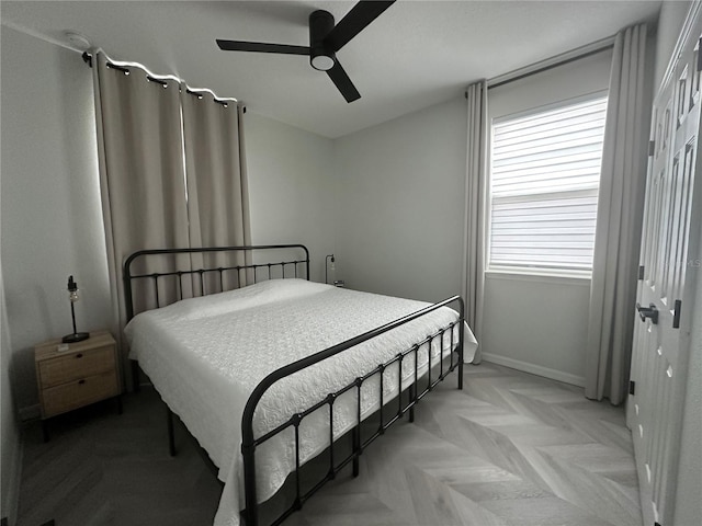 bedroom with light parquet flooring, ceiling fan, and a closet