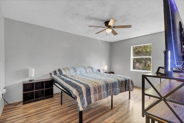 bedroom featuring ceiling fan, hardwood / wood-style floors, and a textured ceiling