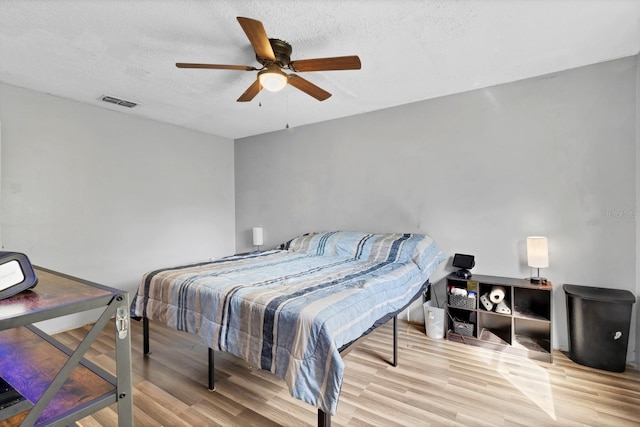 bedroom featuring ceiling fan, hardwood / wood-style floors, and a textured ceiling