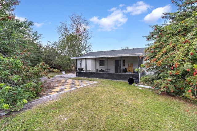 rear view of house featuring a sunroom, a yard, and a patio area