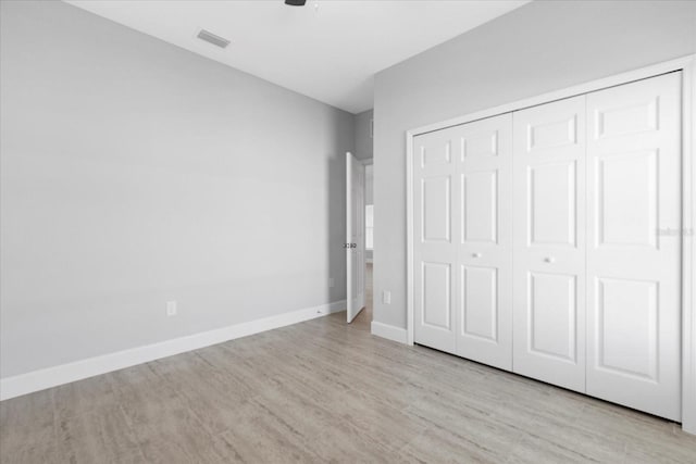 unfurnished bedroom with light wood-type flooring and a closet