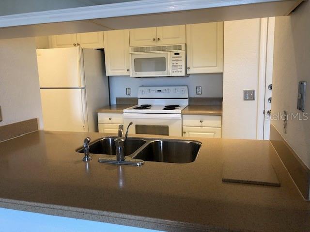 kitchen with sink, white cabinets, and white appliances