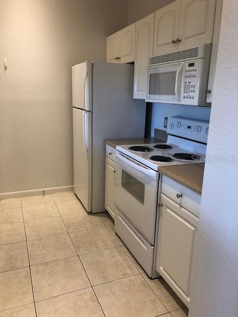 kitchen featuring white cabinetry, white appliances, and light tile patterned floors