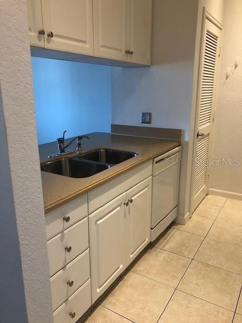 kitchen with white cabinetry, white dishwasher, sink, and light tile patterned floors