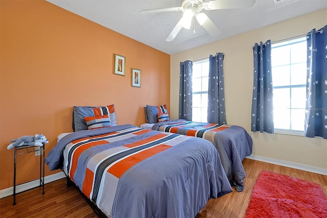 bedroom featuring hardwood / wood-style flooring, ceiling fan, and multiple windows