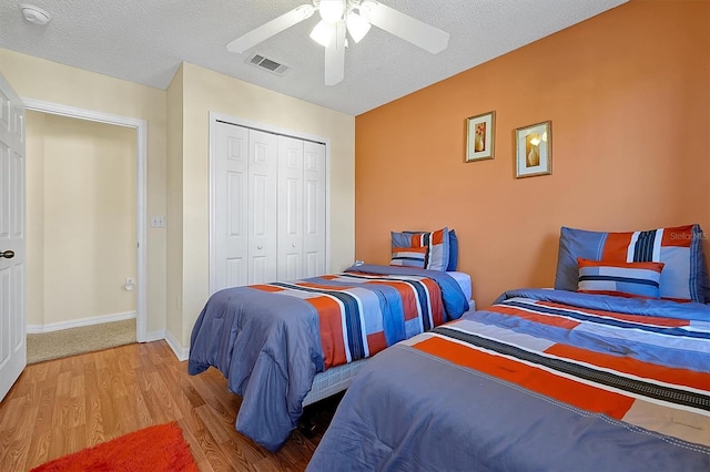 bedroom featuring light hardwood / wood-style floors, a textured ceiling, ceiling fan, and a closet