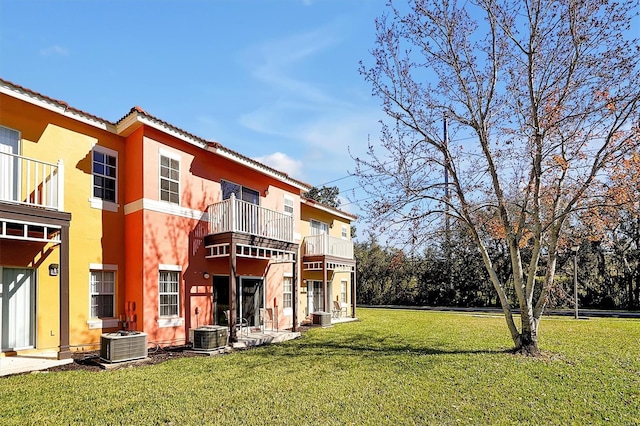 rear view of property featuring a balcony, central AC, and a lawn