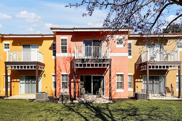 rear view of property with a balcony, central AC, a patio area, and a lawn