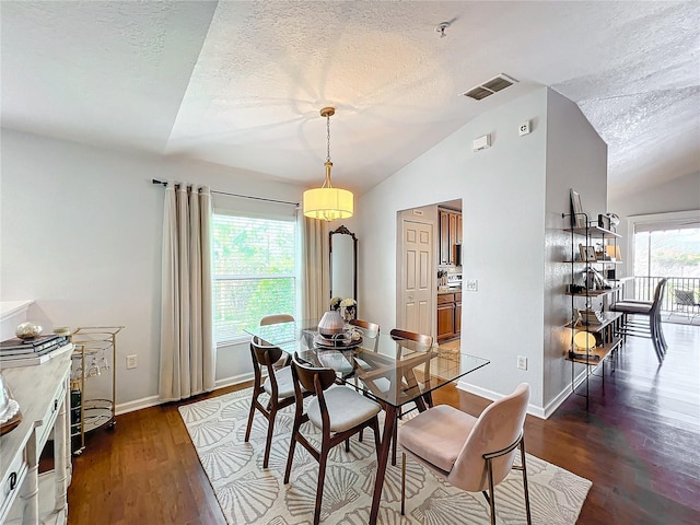 dining area with lofted ceiling, dark wood-type flooring, a textured ceiling, and plenty of natural light