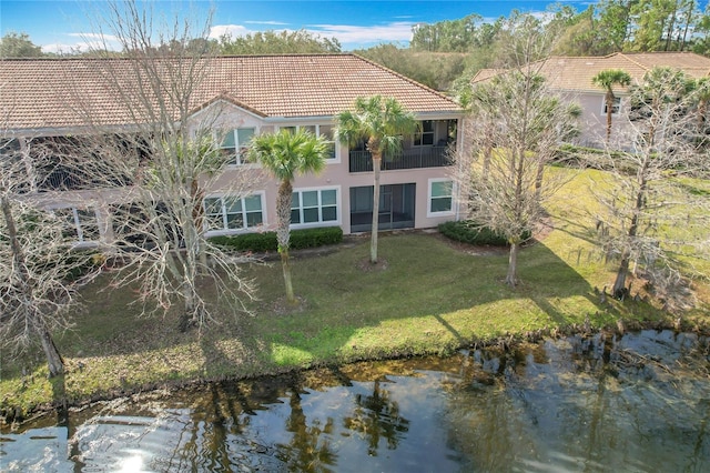 back of house featuring a lawn and a water view