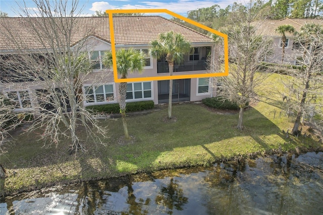 rear view of house featuring a water view and a lawn