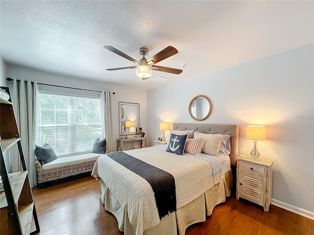 bedroom with ceiling fan, dark hardwood / wood-style floors, and a textured ceiling