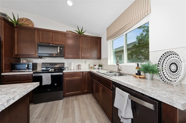 kitchen with vaulted ceiling, sink, decorative backsplash, stainless steel appliances, and light wood-type flooring