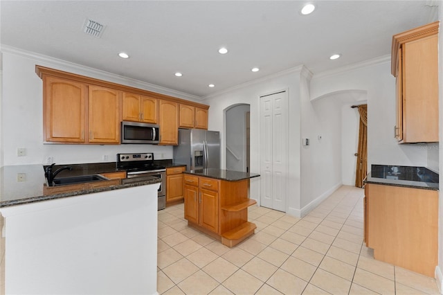 kitchen featuring sink, a center island, ornamental molding, appliances with stainless steel finishes, and dark stone counters