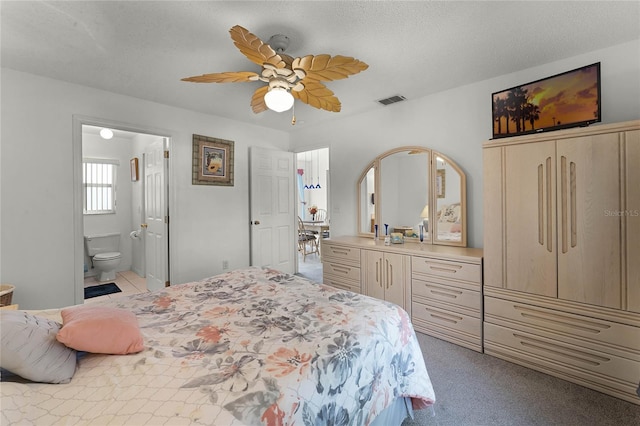 carpeted bedroom featuring a textured ceiling, ceiling fan, and ensuite bath