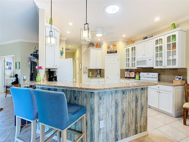 kitchen featuring light stone counters, white cabinetry, kitchen peninsula, pendant lighting, and white appliances