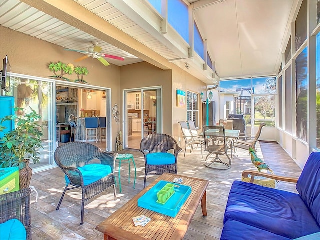 sunroom with ceiling fan and beam ceiling