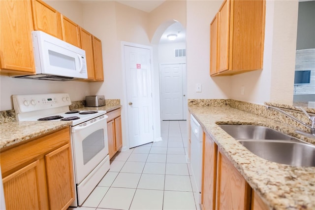 kitchen featuring sink, light stone counters, light brown cabinets, light tile patterned floors, and white appliances