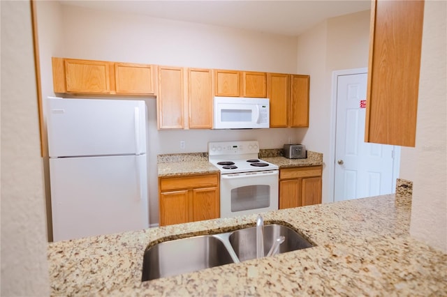 kitchen featuring sink, light stone counters, and white appliances