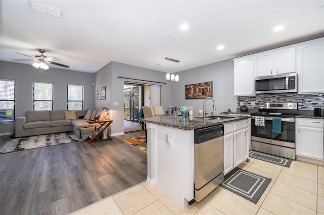 kitchen with sink, dark stone countertops, white cabinetry, hanging light fixtures, and stainless steel appliances