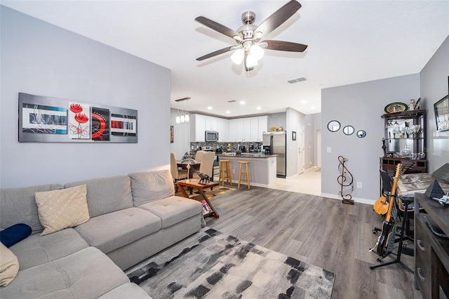 living room with ceiling fan and light hardwood / wood-style floors