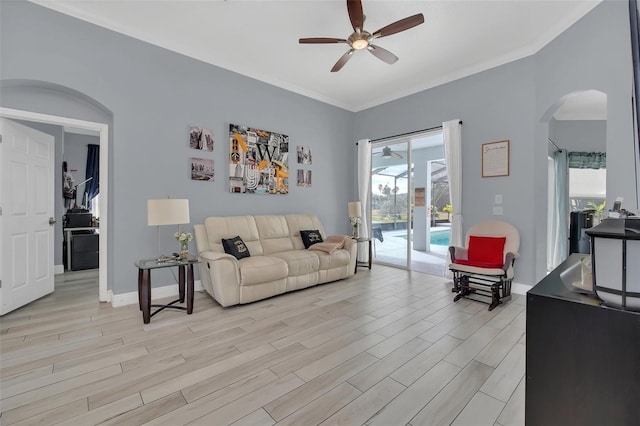 living room featuring a wealth of natural light, ornamental molding, ceiling fan, and light wood-type flooring