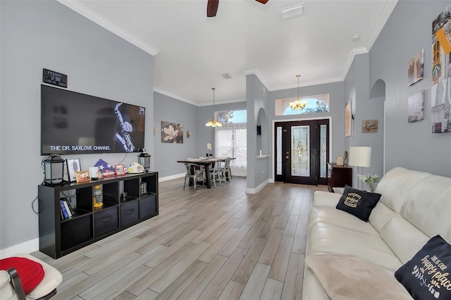 living room with crown molding, ceiling fan with notable chandelier, and light hardwood / wood-style flooring