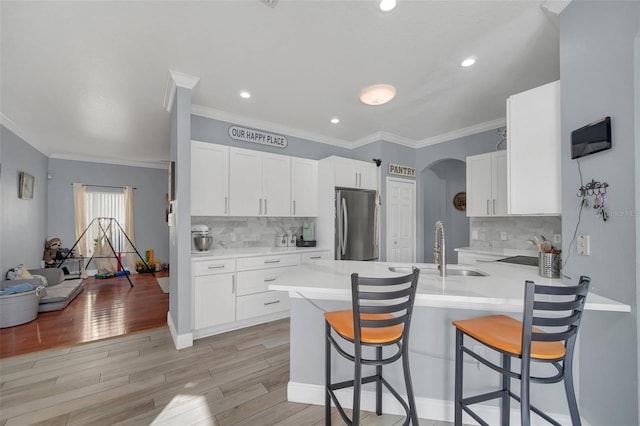 kitchen with sink, stainless steel fridge, a kitchen breakfast bar, white cabinets, and kitchen peninsula