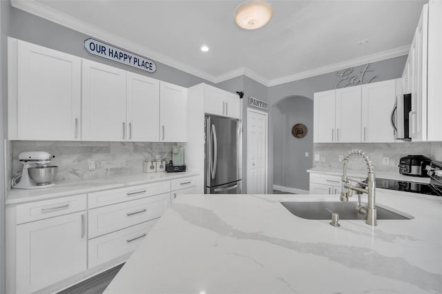 kitchen with sink, stainless steel appliances, white cabinets, and light stone countertops