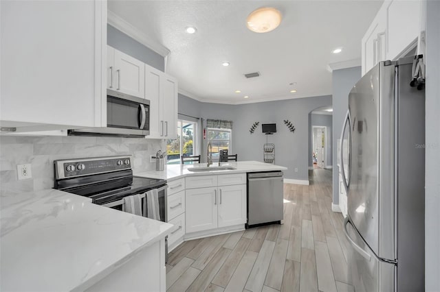 kitchen with white cabinetry, appliances with stainless steel finishes, sink, and light stone counters