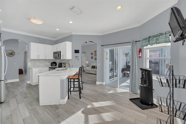 kitchen featuring sink, crown molding, appliances with stainless steel finishes, a kitchen island with sink, and white cabinets