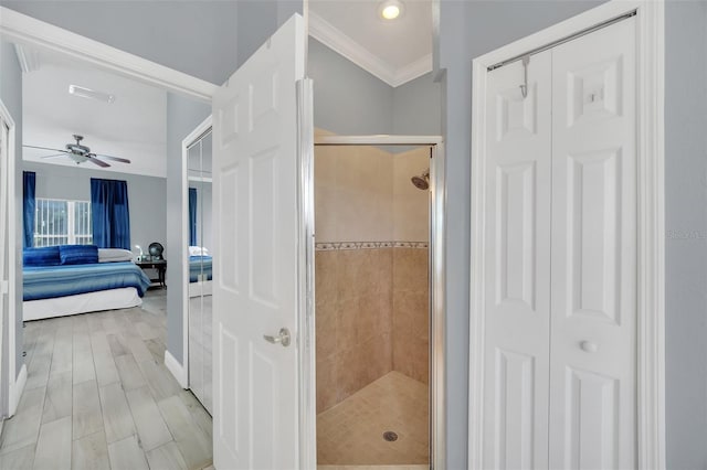 bathroom featuring hardwood / wood-style flooring, crown molding, ceiling fan, and a shower with shower door