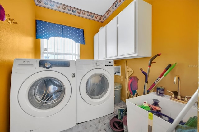 clothes washing area with cabinets, washer and clothes dryer, and sink