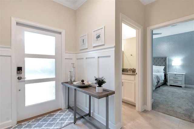 doorway to outside with ornamental molding, plenty of natural light, sink, and light carpet