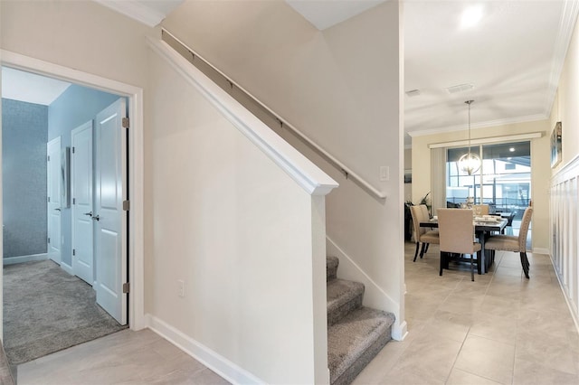 staircase featuring tile patterned flooring, crown molding, and an inviting chandelier