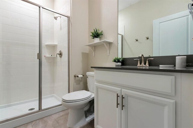 bathroom featuring vanity, walk in shower, tile patterned floors, and toilet