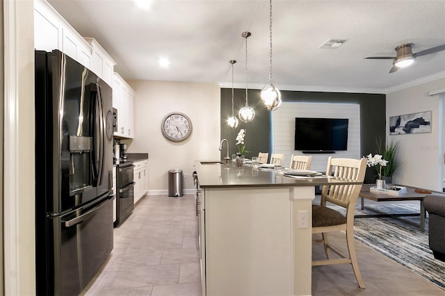 kitchen with decorative light fixtures, sink, white cabinets, a kitchen bar, and black appliances