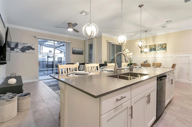 kitchen featuring pendant lighting, white cabinetry, sink, stainless steel dishwasher, and a center island with sink