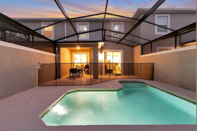 pool at dusk with a lanai and a patio