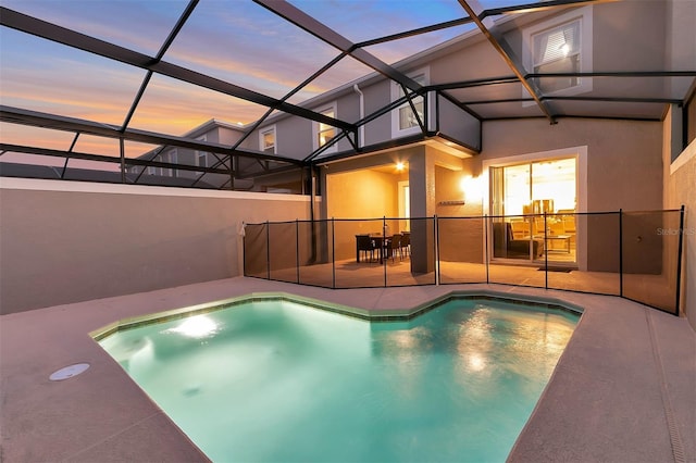 pool at dusk with a lanai and a patio area