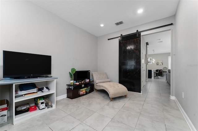 sitting room featuring light tile patterned flooring, a barn door, and a textured ceiling