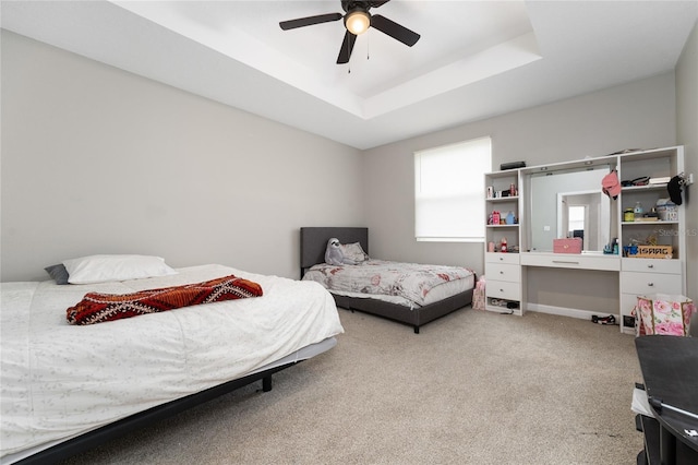 bedroom featuring a raised ceiling, ceiling fan, and carpet