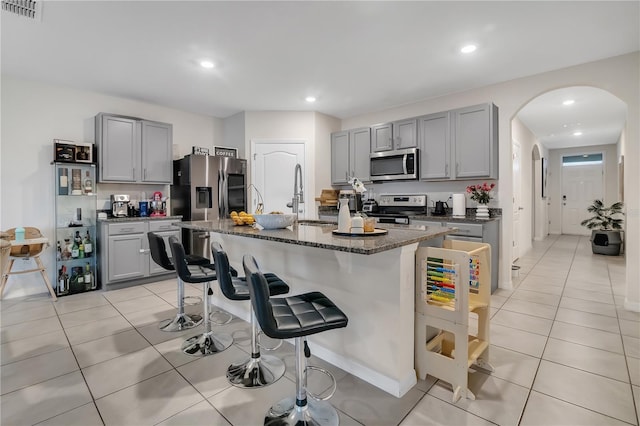 kitchen featuring appliances with stainless steel finishes, a kitchen island with sink, and gray cabinetry