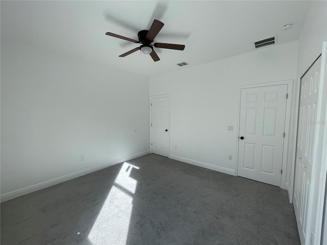 unfurnished room with dark colored carpet and ceiling fan