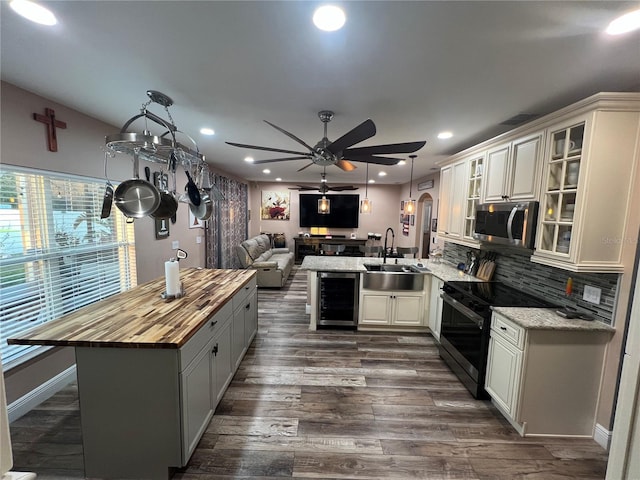 kitchen with butcher block counters, sink, kitchen peninsula, range with electric cooktop, and beverage cooler