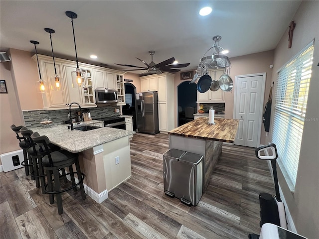 kitchen featuring appliances with stainless steel finishes, decorative light fixtures, sink, decorative backsplash, and kitchen peninsula