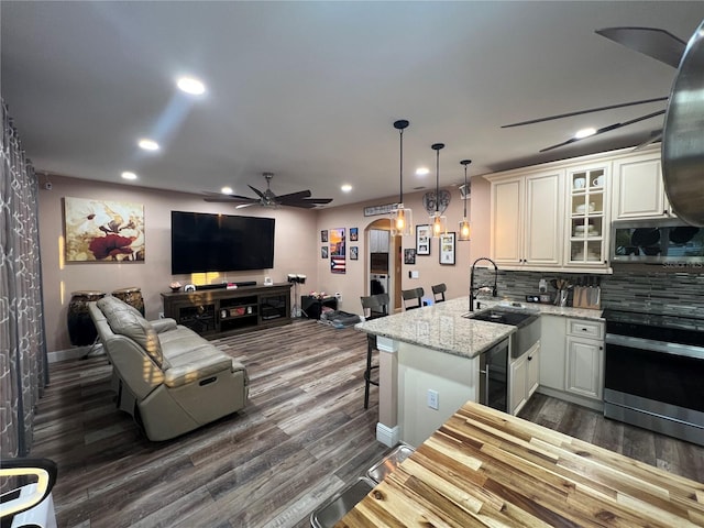 kitchen with appliances with stainless steel finishes, tasteful backsplash, white cabinets, kitchen peninsula, and light stone countertops