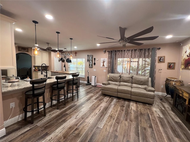 living room featuring dark wood-type flooring, ceiling fan, and sink